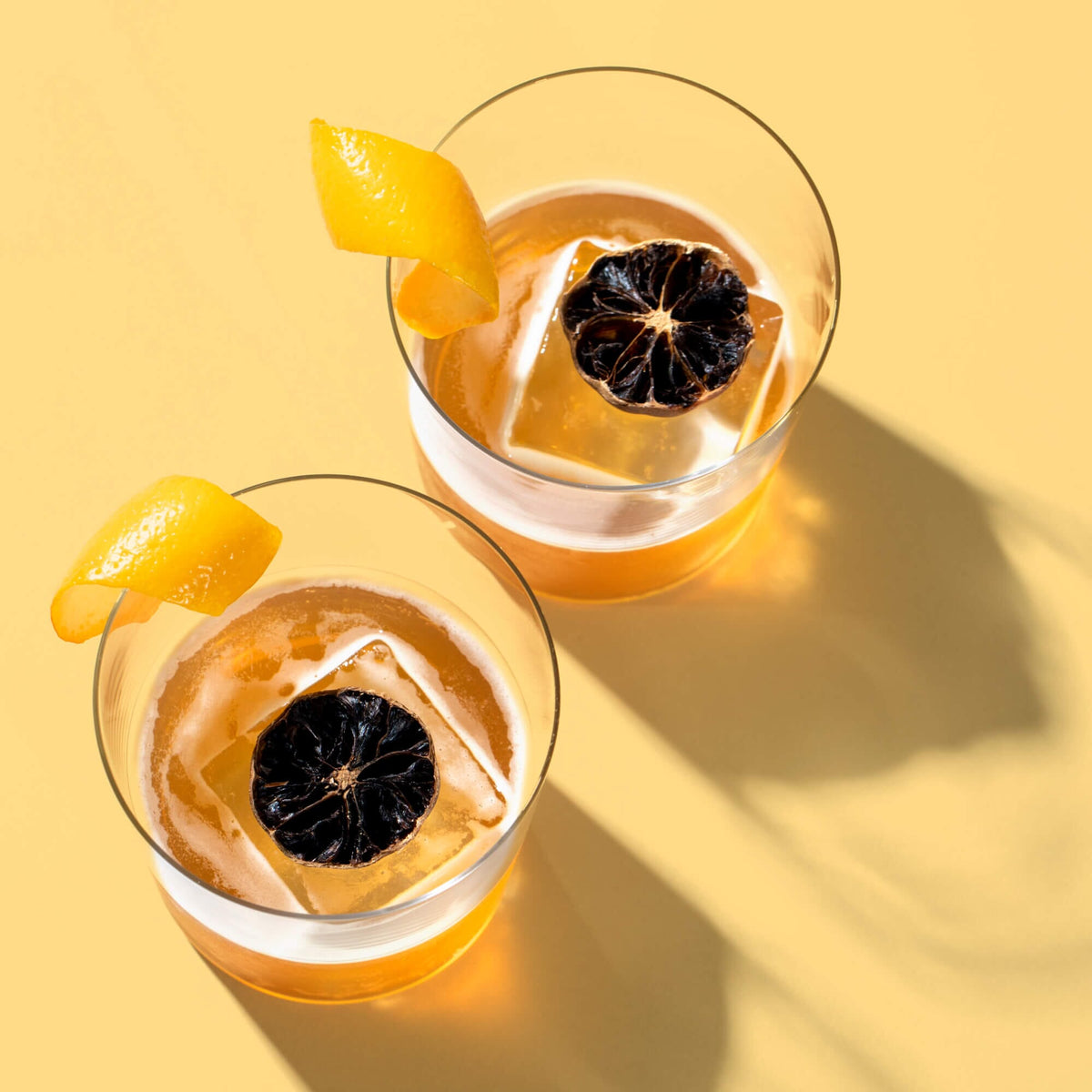 Two glasses of Black Lemon cocktails with orange slices and ice from Rishi Tea & Botanicals.