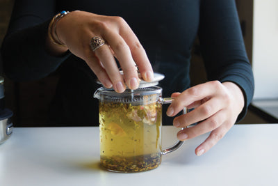 Hand closing the lid to infuse the tea with the Simple Brew