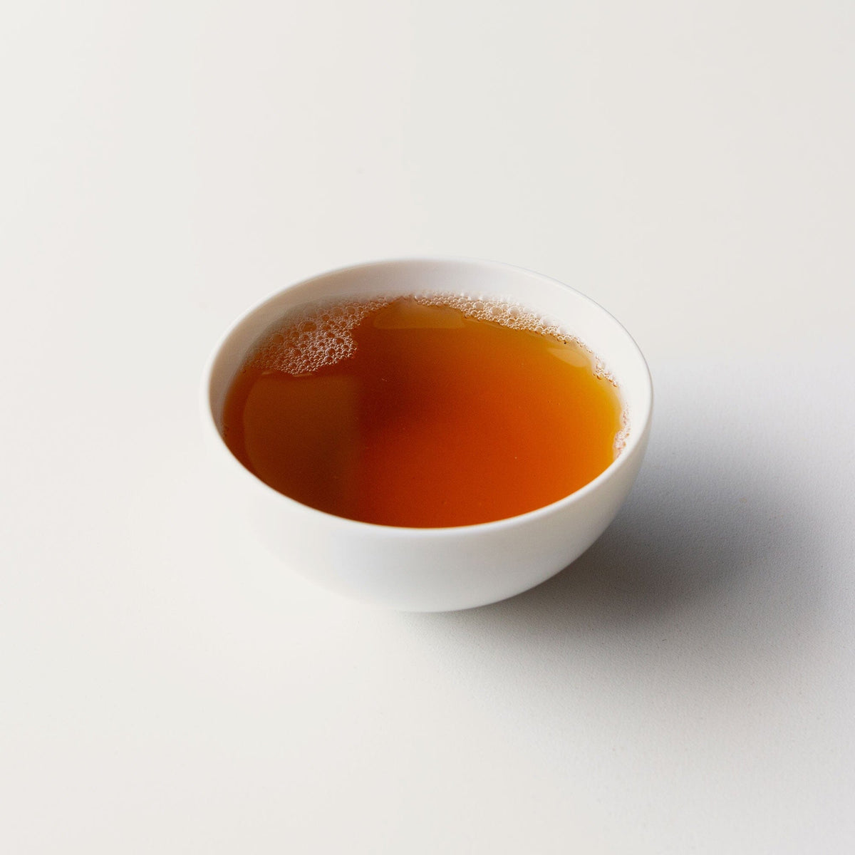 A bowl of Old Trees Lincang Sheng Pu’er Cake tea on a white background by Rishi Tea & Botanicals.