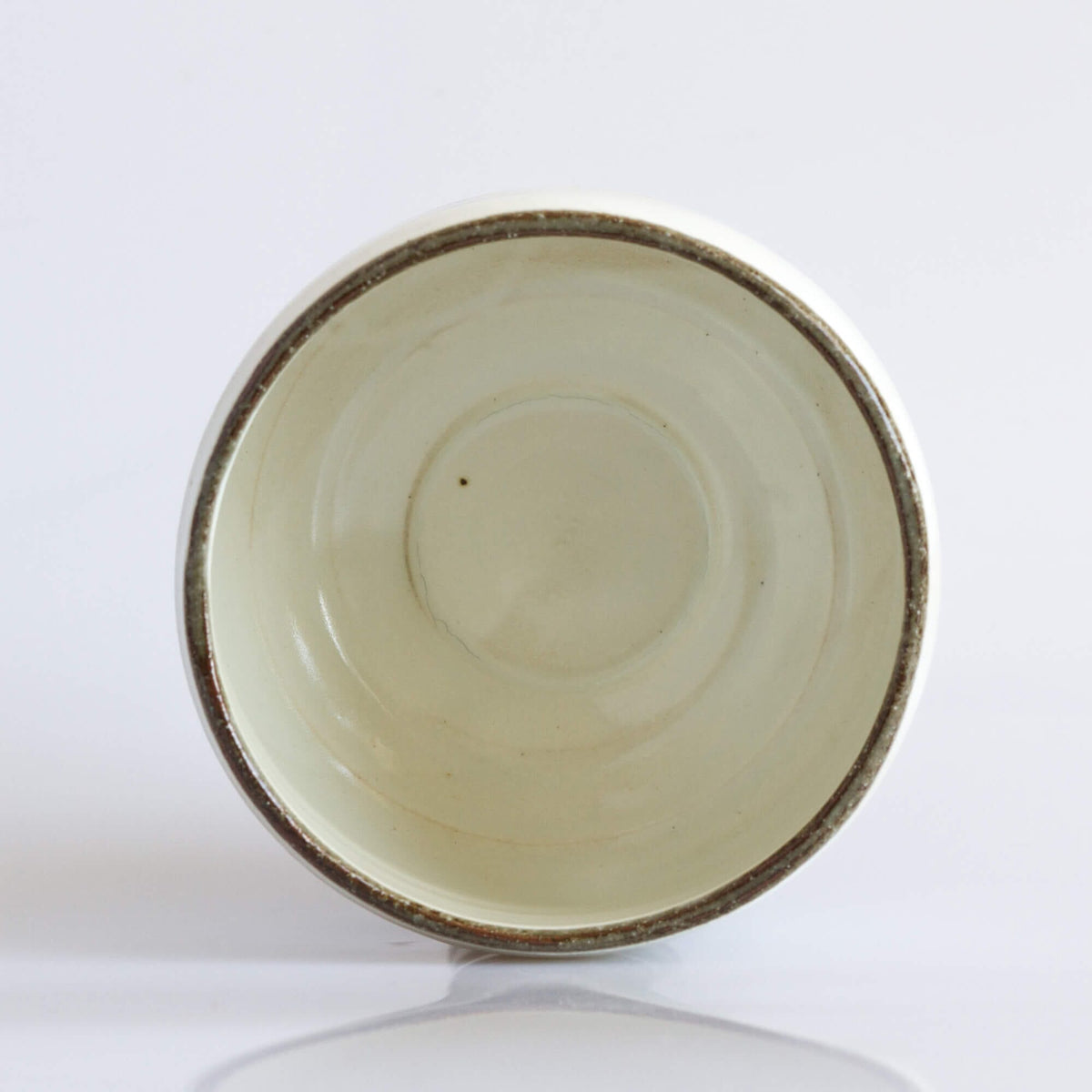 A small Wabi Sabi Raku Matcha Bowl with a volume of 21oz on a white surface by Rishi Tea & Botanicals.