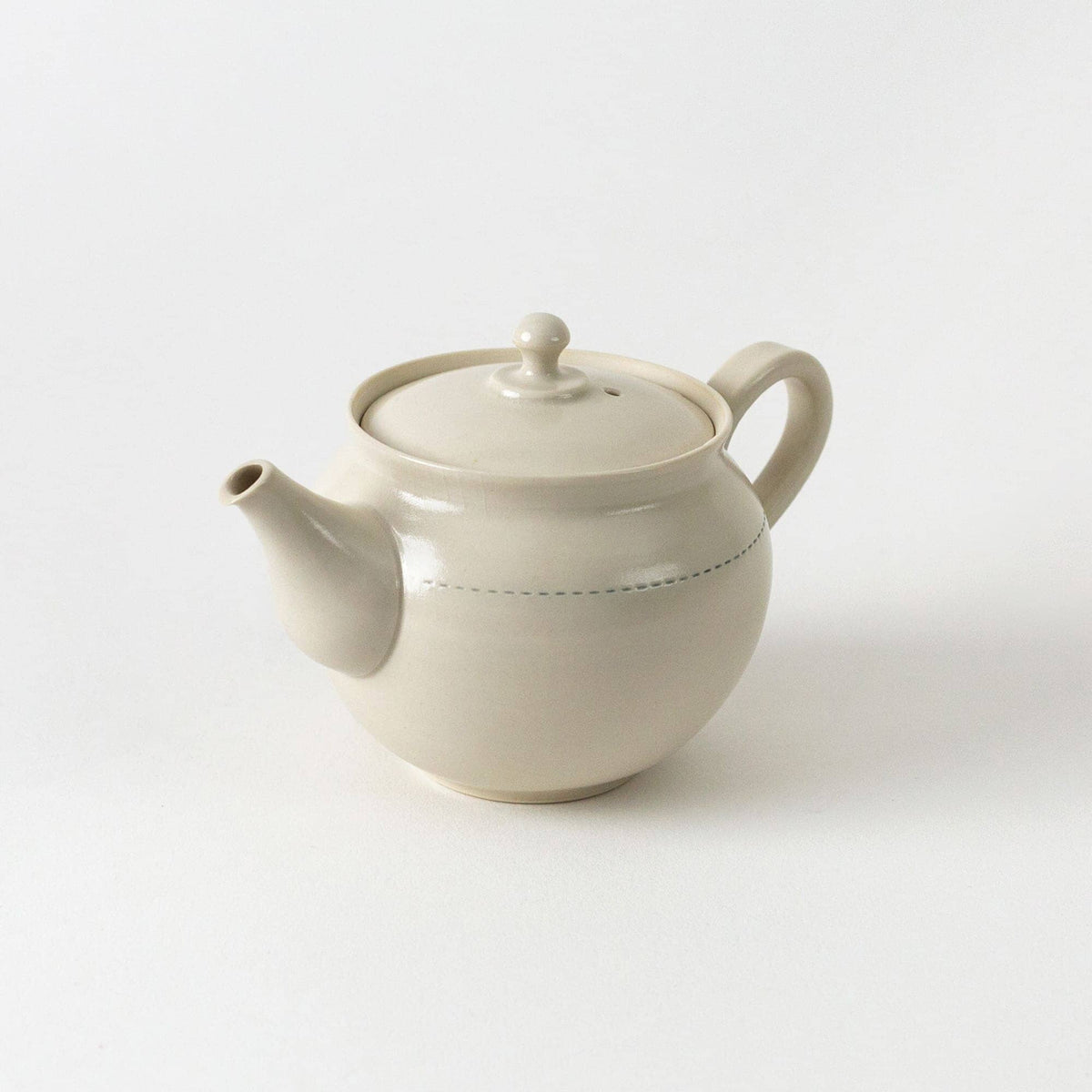 A beige ceramic kyusu teapot by Rishi Tea & Botanicals, featuring a round body, curved handle, short spout, and lid, set against a plain white background—ideal for a collectible teaware set.