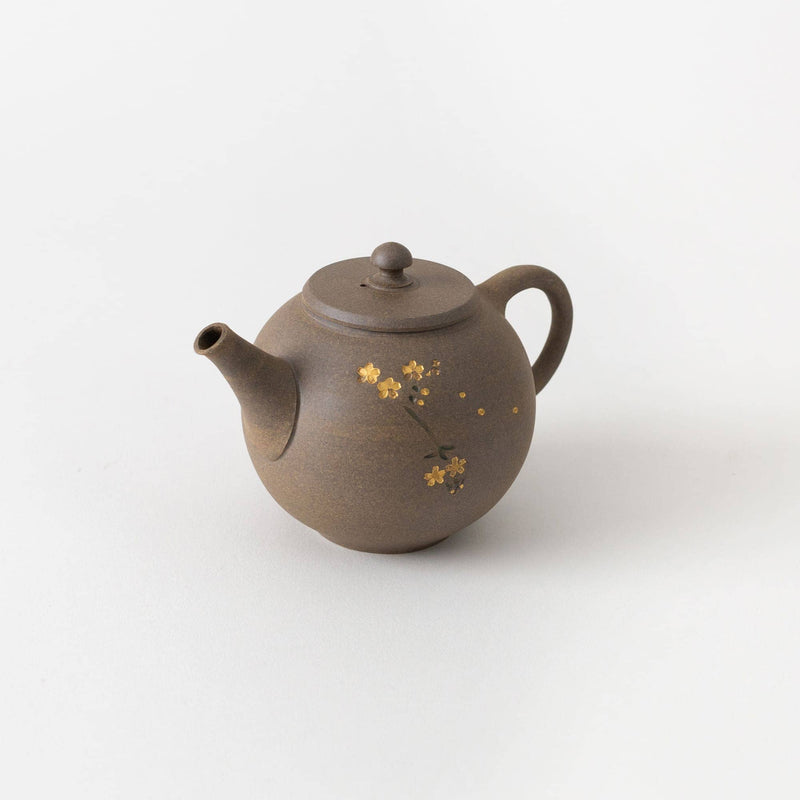 A brown Tokoname kyusu teapot by Chato Co., Ltd. with a round lid and handle, adorned with small yellow chrysanthemum motifs, sits on a plain white surface.