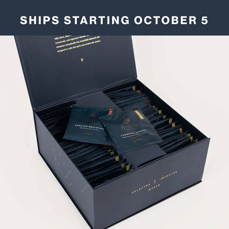 Open box of individually-wrapped sachets featuring Rishi’s artisanal teas, with two packets displayed on top. Text above the image reads, “Ships starting October 5.”.