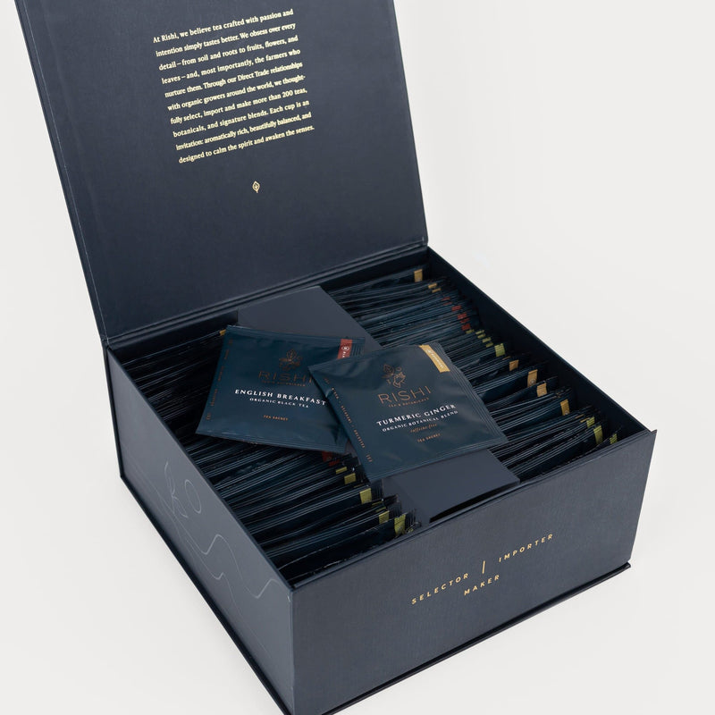 An open black box contains neatly arranged tea sachets. Two sachets, labeled English Breakfast and Teahouse Matcha, are displayed on top.