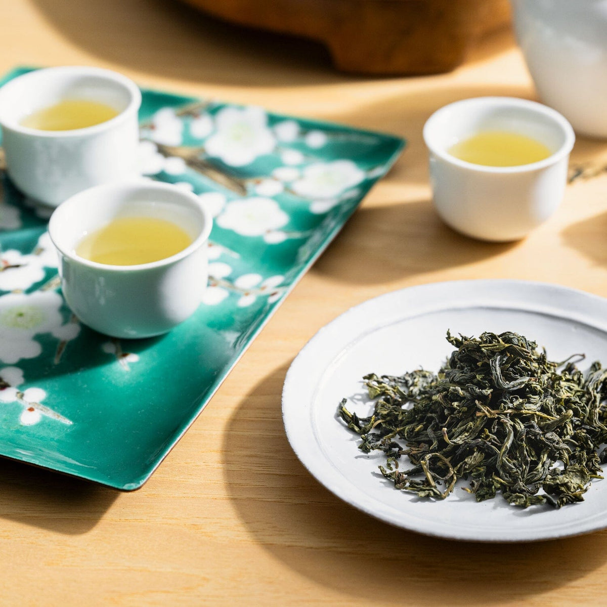 A Taiwan Flight of Tea Bundle from Rishi Tea & Botanicals on a plate next to a cup of oolong tea.
