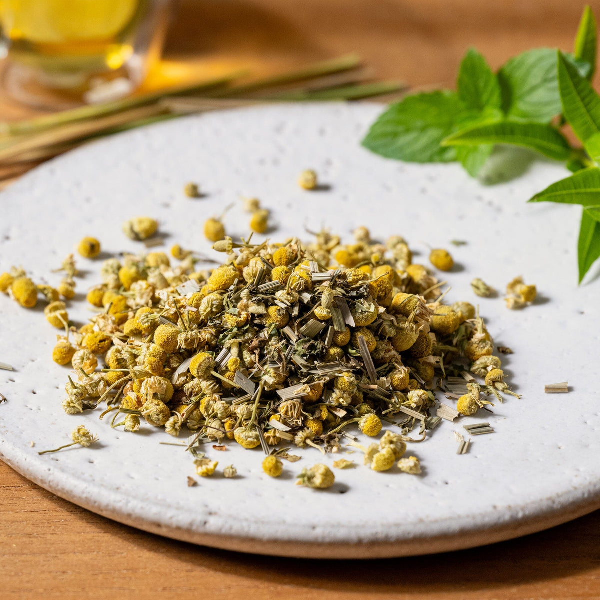 Chamomile Medley tea on a white plate next to a glass of water, Rishi Tea & Botanicals.