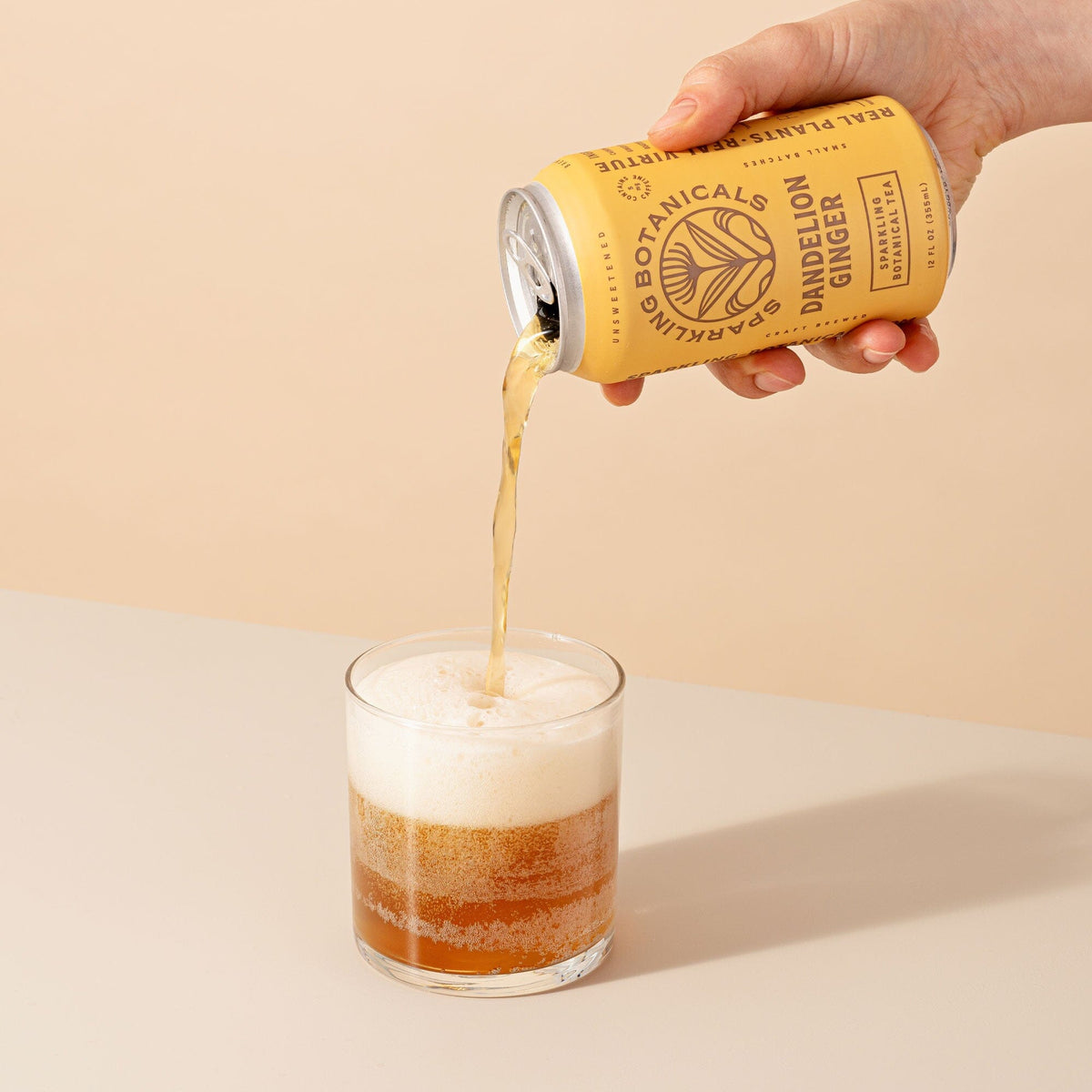 A person pouring Dandelion Ginger beer from Rishi Tea & Botanicals into a glass.