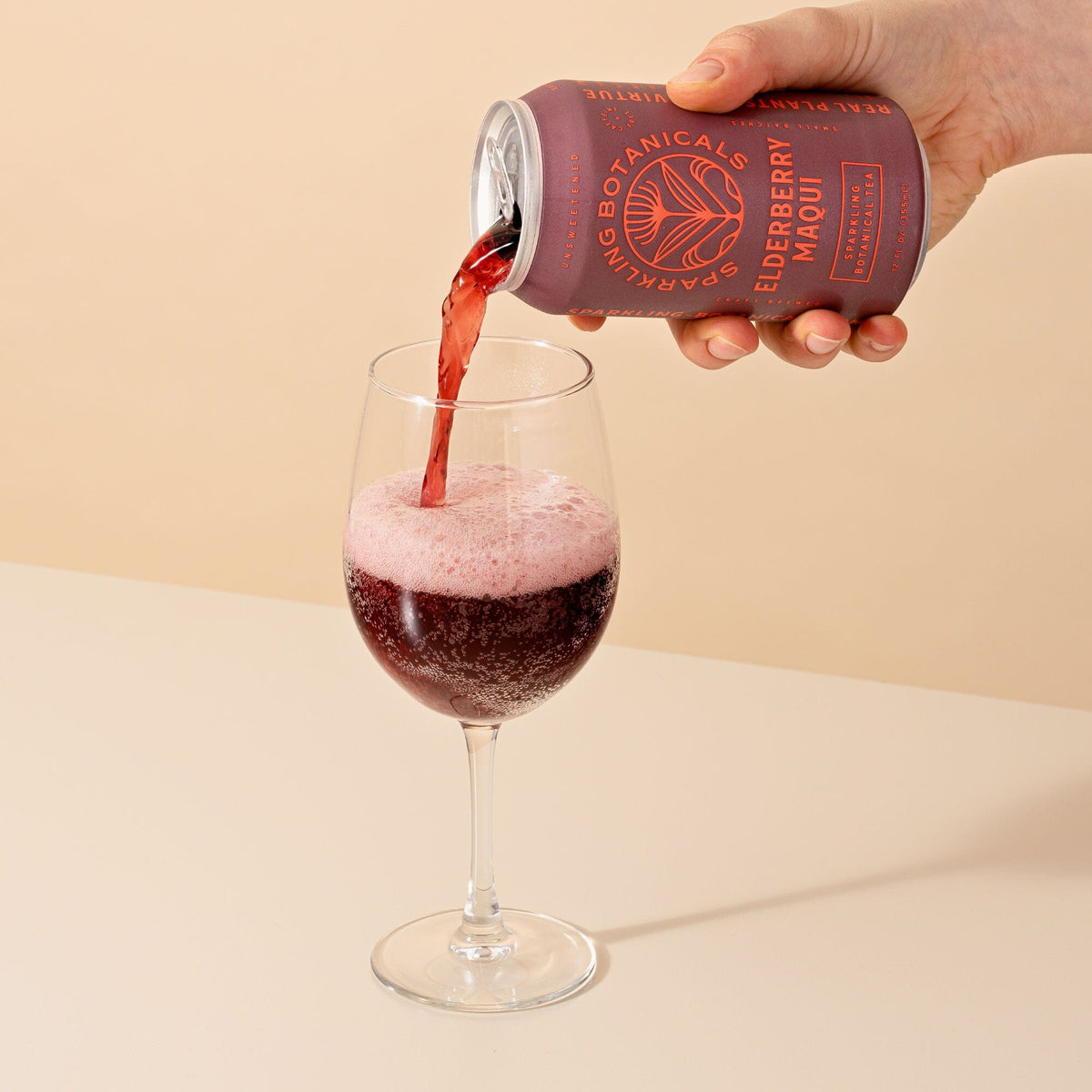 A person pouring Elderberry Maqui from Rishi Tea & Botanicals into a glass of wine.