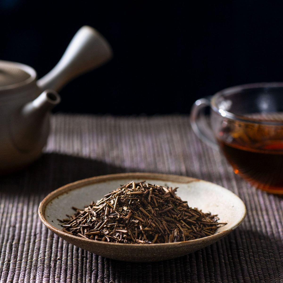 A bowl of Houjicha tea and a Rishi Tea & Botanicals teapot on a table.