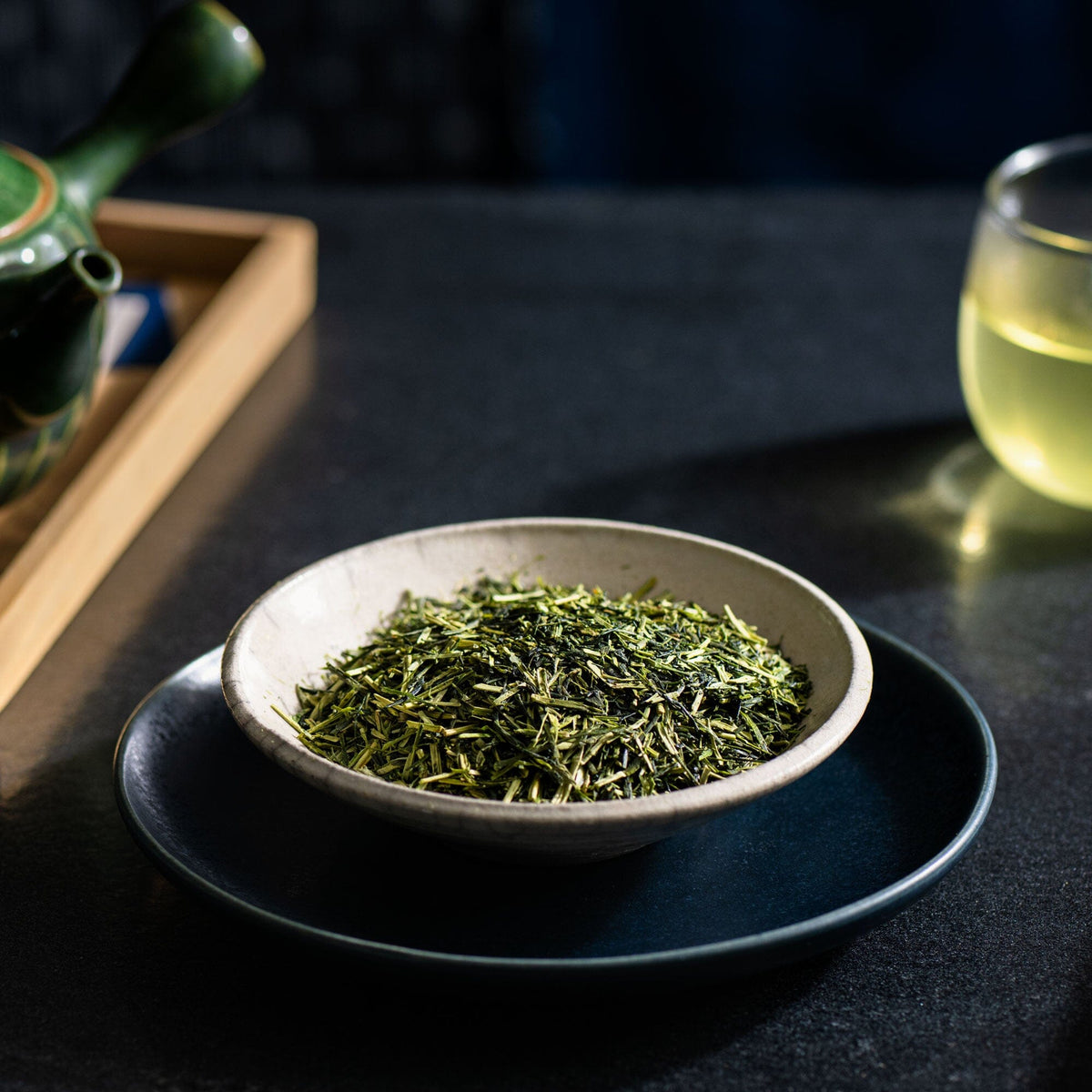 A bowl of Kukicha from Rishi Tea & Botanicals on a table next to a teapot.