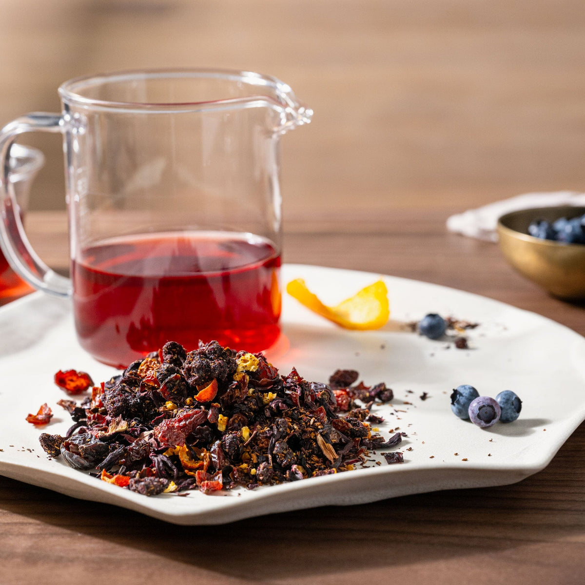 A white plate with Scarlet - Organic berries and a pitcher of Rishi Tea & Botanicals tea.