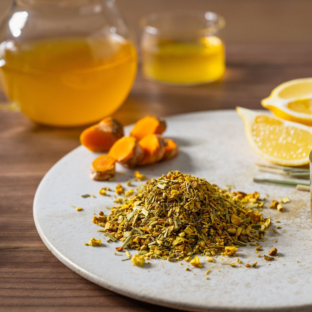 A plate with a cup of Rishi Tea & Botanicals' Turmeric Ginger tea and a slice of lemon.