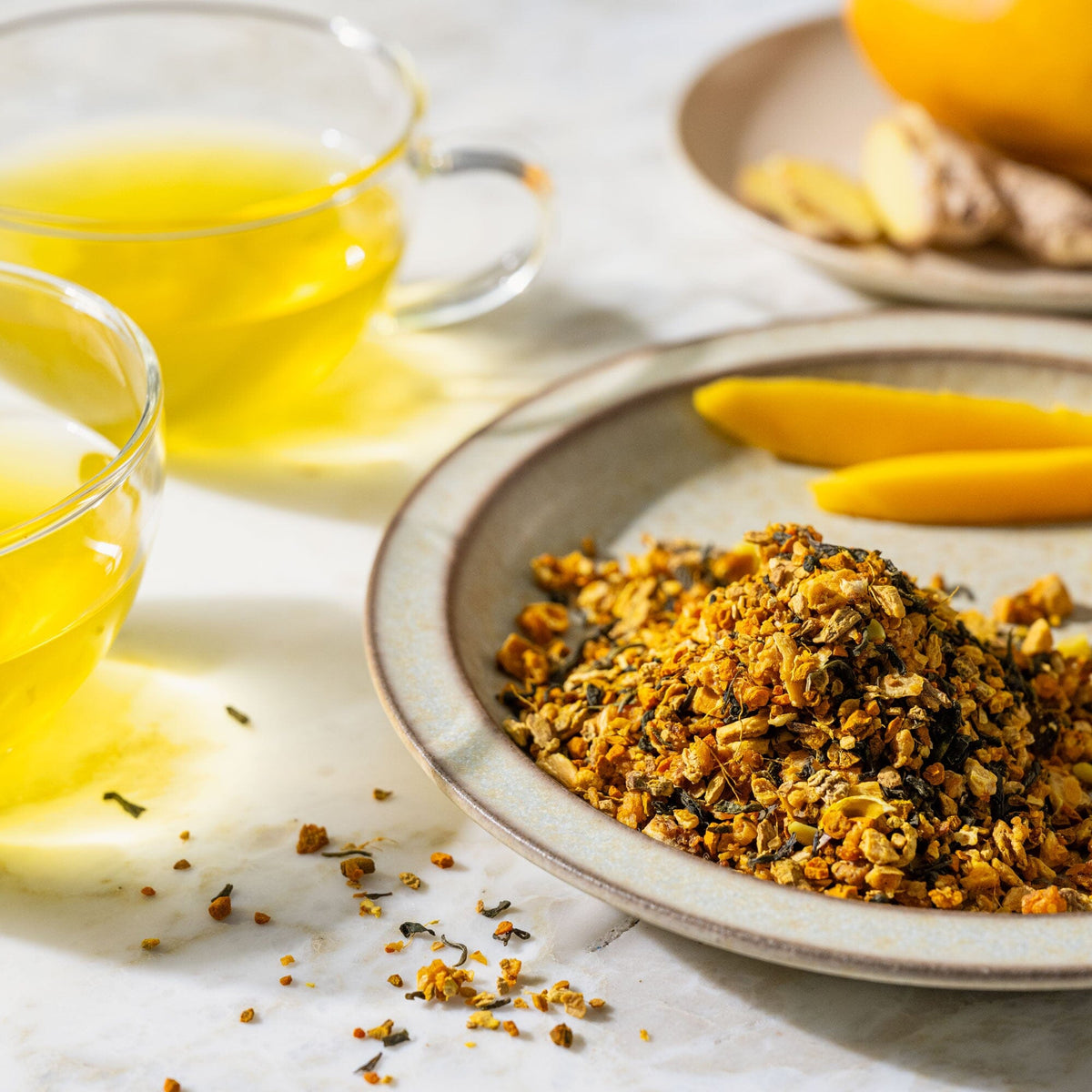 A bowl of Turmeric Mango granola on a table next to a cup of tea from Rishi Tea & Botanicals.