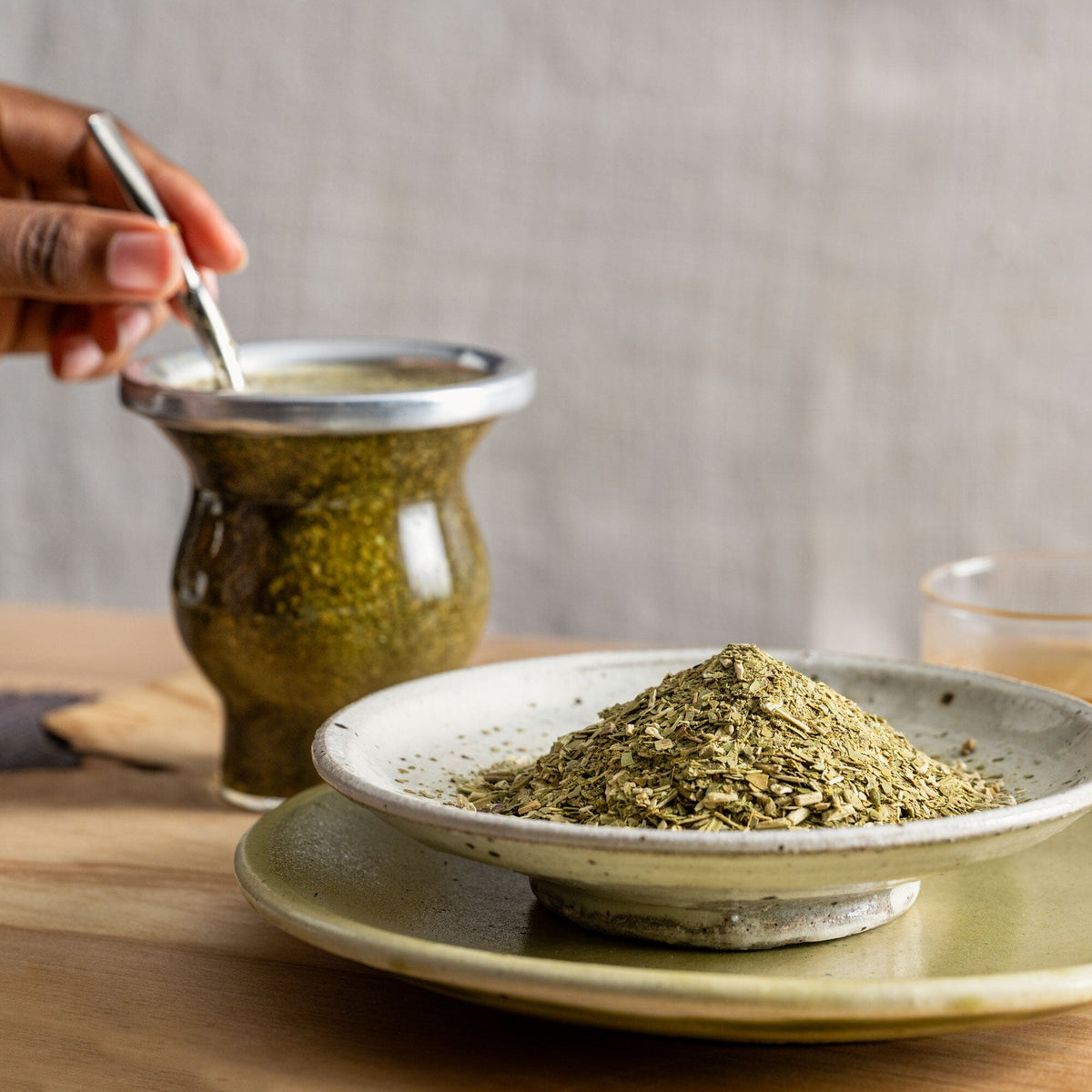 A person pouring a spoonful of Rishi Tea & Botanicals Yerba Mate into a bowl on a table.
