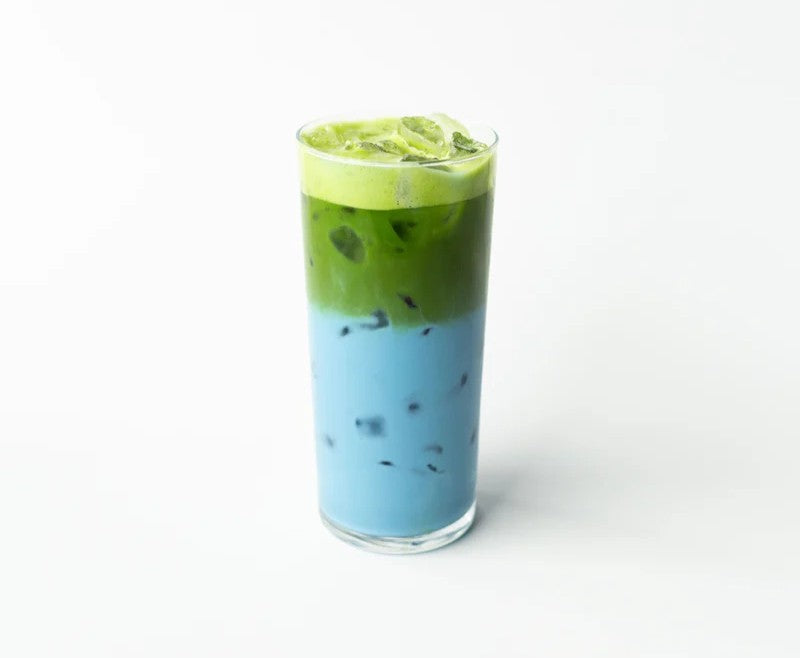 Two-layered drink with matcha on top and Blue Tea Jasmine on bottom in a clear glass on a white background