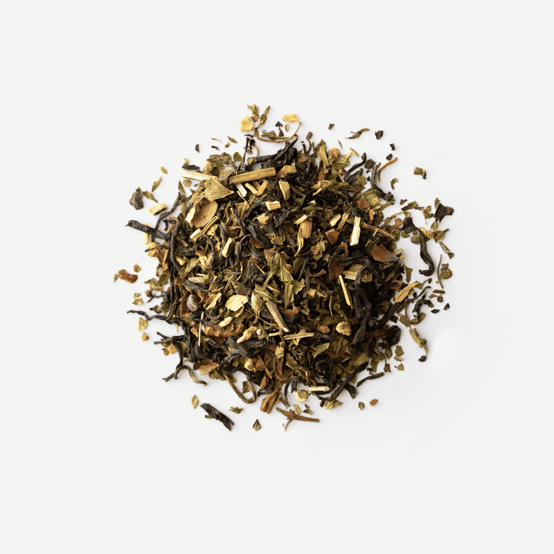 A pile of loose leaf winter tea blend by Rishi Tea & Botanicals, featuring green, brown, and black dried leaves with small pieces, displayed on a white background.