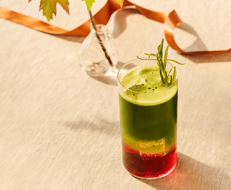 Layered Sparkle Spice Matcha Latte with green, yellow, and red colors in a glass on a textured surface.