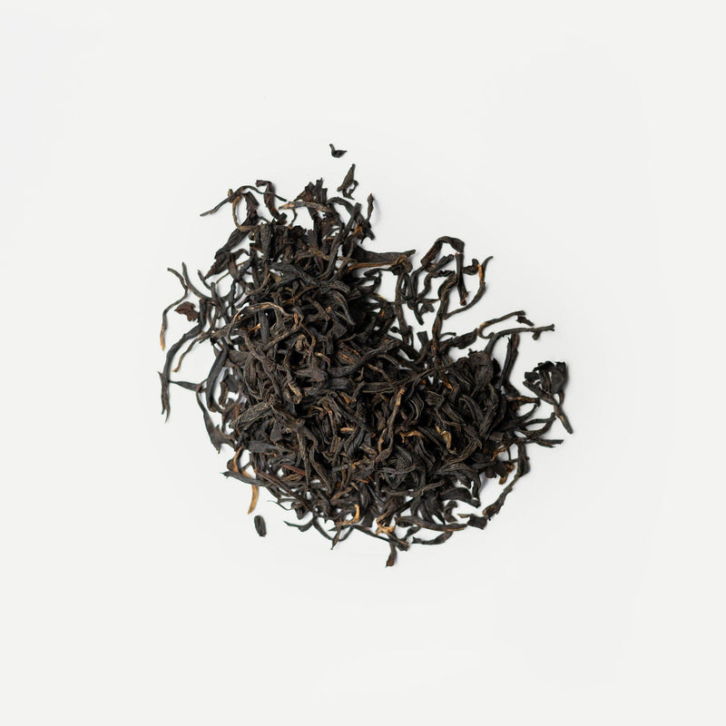 A pile of antioxidant-rich, organic tea leaves sits on a white background, showcasing the exquisite Yunnan Purple Buds from Rishi Tea & Botanicals.