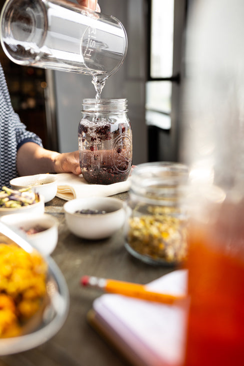 Person adding water to jar of botanicals