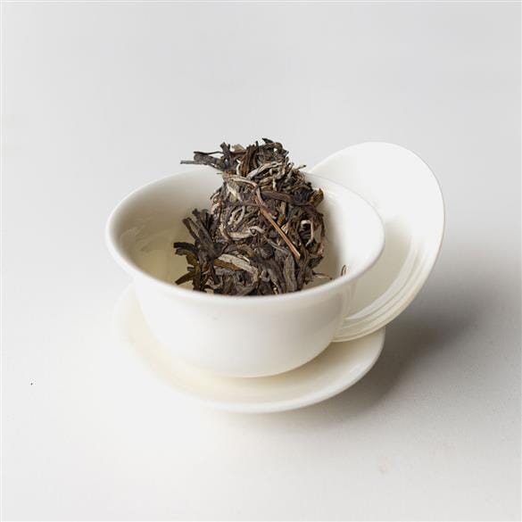 Laos Sheng Pu’er Tea Brick Vintage 2022 from Rishi Tea & Botanicals in a white cup on a white surface.