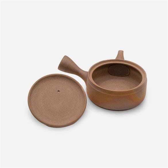 A Cera-Mesh Kyusu Teapot by Rishi Tea & Botanicals with a lid next to it, showcasing its natural coloring.