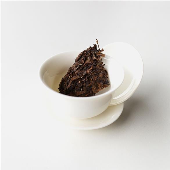 A cup of tea with a piece of Doi Wawee Shaihong Spring Cake from Rishi Tea & Botanicals in it.